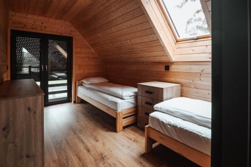 a attic room with two beds and a window at Ptasia ferajna - domki całoroczne w Dolinie Baryczy in Milicz
