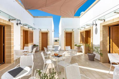 an outdoor patio with white chairs and tables at Lido Marini Rooms Affittacamere B&B in Lido Marini