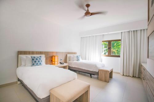 a hotel room with two beds and a window at Hodges Bay Resort & Spa, an HQ Luxury Resort & Residences in Saint Johnʼs