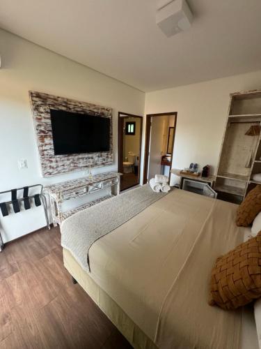 a bedroom with a large bed with a tv on the wall at Pousada da Germana in Fernando de Noronha