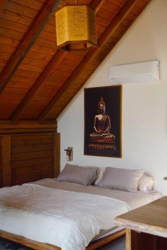 a bedroom with a bed with a picture on the wall at Villa Bali Praia do Rosa in Imbituba