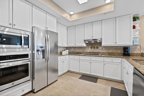 una cucina con armadietti bianchi ed elettrodomestici in acciaio inossidabile di Indigo East Unit 1005E a Pensacola