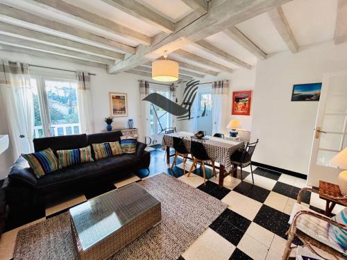 un salon avec un canapé noir et une table dans l'établissement Villa Georgette - Proche des plages, à La Tremblade
