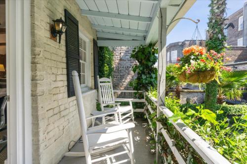 a porch with white chairs and flowers on a house at 16 E Jones Carriage House in Savannah