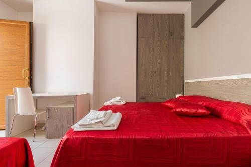 a bedroom with a red bed with red sheets and a desk at Lido Marini Rooms Affittacamere B&B in Lido Marini