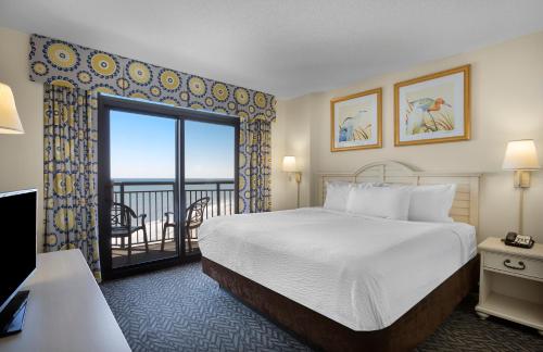 a hotel room with a bed and a balcony at Ocean Reef Resort in Myrtle Beach