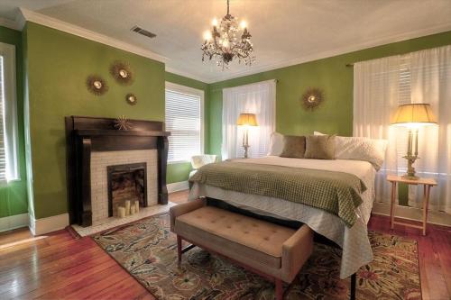 a bedroom with green walls and a bed and a fireplace at 121 W Jones Suite Loft 4f in Savannah