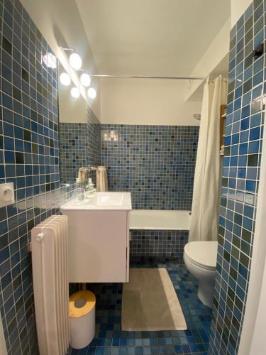 La salle de bains est pourvue de carrelage bleu, d'un lavabo et de toilettes. dans l'établissement Lovely studio apartment, à Nice