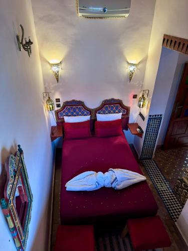 a bedroom with a bed with red sheets and pillows at Riad Hamad Tijani in Fès