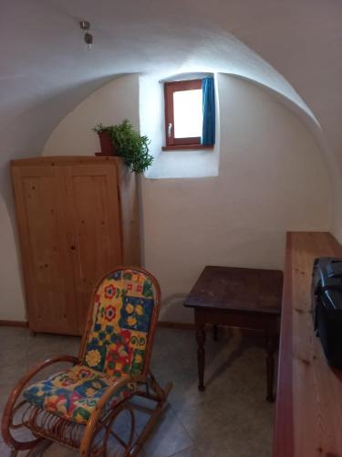 a room with a chair and a table and a window at Ala Roda- appartamento in Ziano di Fiemme