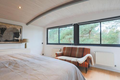 een slaapkamer met een bed, een stoel en ramen bij Entre Terre Et Mer in Locquirec