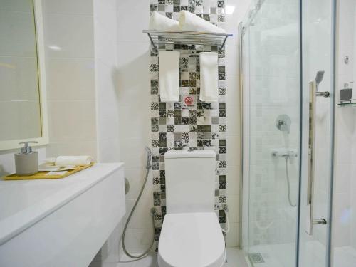 a white bathroom with a toilet and a shower at Coconut Tree Hulhuvilla Beach in Hulhumale