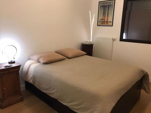 a bedroom with a bed with a lamp on a table at T3 neuf plein sud Arcachon première ligne in La Teste-de-Buch