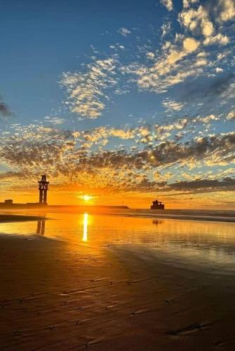 a sunset on the beach with a lighthouse in the distance at la perle rare de Sidi Ifni in Sidi Ifni