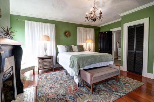 a bedroom with green walls and a bed and a fireplace at 121 W Jones Suite Loft 4f in Savannah