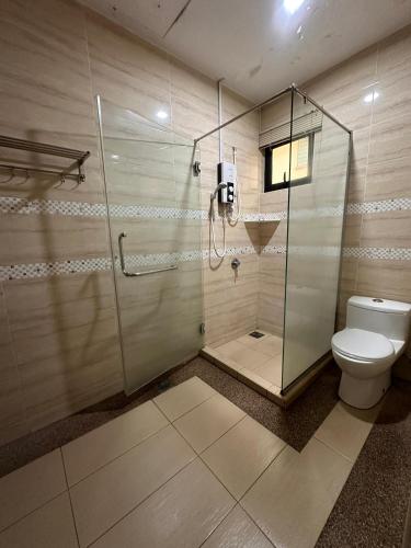 a bathroom with a glass shower and a toilet at Maxwell inn in Taiping