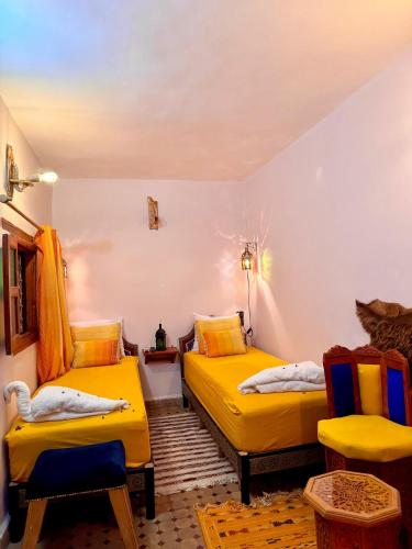 two beds in a room with yellow beds at Riad Hamad Tijani in Fès