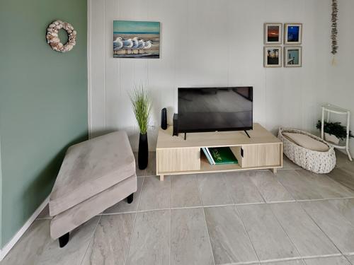 Una sala de estar con un televisor de pantalla plana y una silla. en Nautical Nook, en Rockport