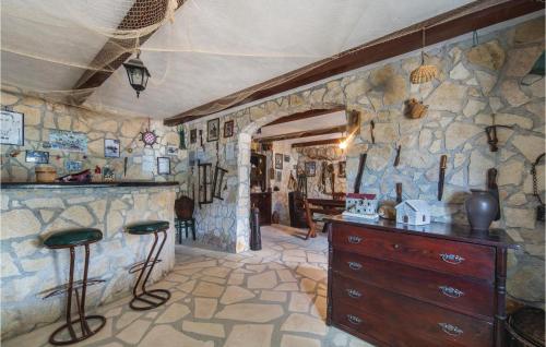 a kitchen with a stone wall with a dresser and stools at One-Bedroom Holiday Home In Rogotin in Rogotin