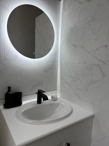 une salle de bain blanche avec un lavabo et un miroir dans l'établissement Grand T2 - Rue de la République, à Orléans