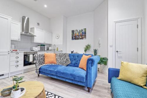 a living room with a blue couch and a kitchen at Chelmsford City Central Ground Floor Apartment Next To Town Centre in Chelmsford