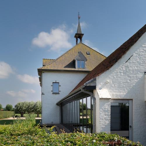 an external view of a white building with a church steeple at 't Convent in Lo-Reninge