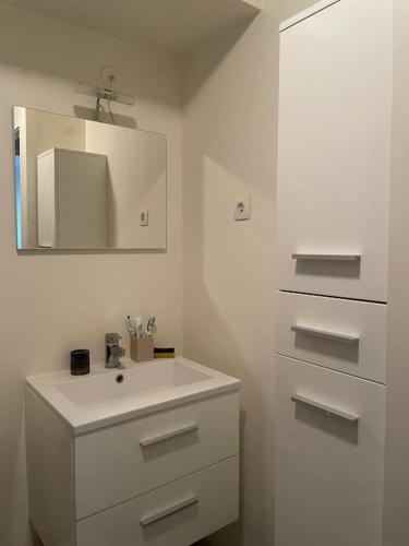 une salle de bain blanche avec un lavabo et un miroir dans l'établissement Double room in a shared duplex flat 15 mins from La Defense Arena - Business Center, à Nanterre