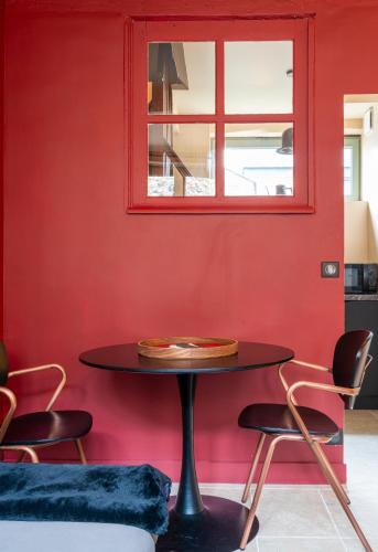 une table dans une pièce avec un mur rouge dans l'établissement La Mondaine - idéalement situé, charme, à Honfleur
