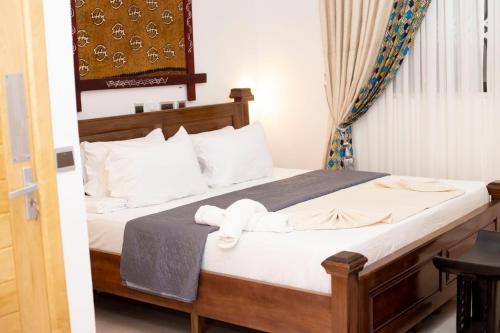 a bedroom with a bed with white sheets at Asantewaa Premier Hotel in Kumasi