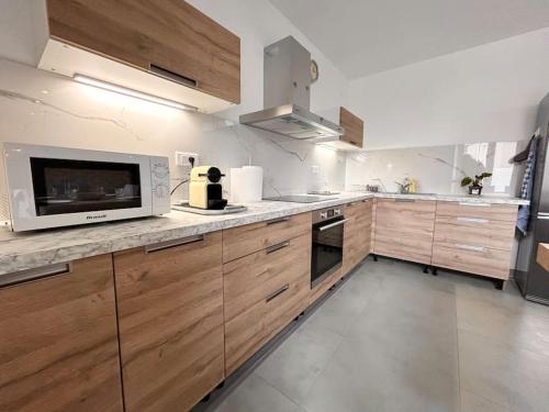 une grande cuisine avec des placards en bois et un four micro-ondes dans l'établissement Appartement neuf Mulhouse, à Mulhouse