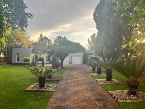 a brick walkway in front of a house with palm trees at B3 Self-catering accommodation Potch in Potchefstroom