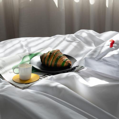 a plate of food and a cup on a bed at Fits Living in Athens