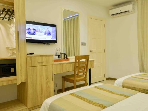 a hotel room with two beds and a television at Coconut Tree Hulhuvilla Beach in Hulhumale