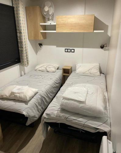 Cette petite chambre comprend 2 lits jumeaux. dans l'établissement Location Mobilhome Bahiana 8 personnes Camping 4 étoiles La Réserve Gastes, à Gastes