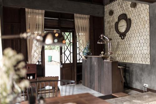a room with a clock on the wall and a table at ONCE (upon a time) Chiang Mai Home in Chiang Mai