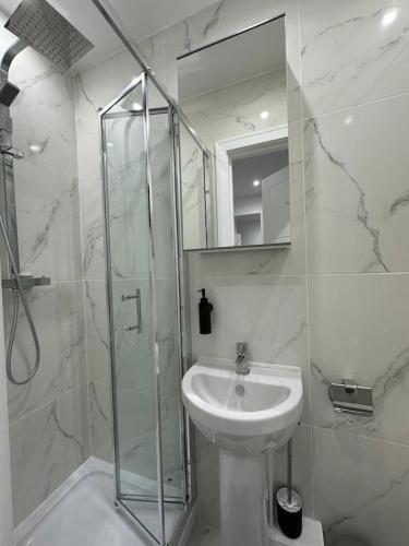 a bathroom with a sink and a glass shower at London Euston 4 minute walk away in London