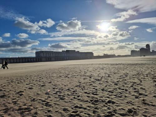 a person walking on a beach with the sun in the sky at Sea Shelter in Ostend