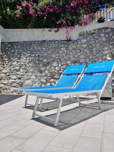 a blue lounge chair sitting next to a stone wall at YourHome - Alisea Home in Nerano