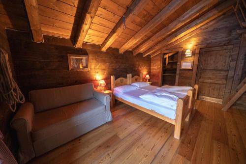 a bedroom with a bed and a couch in a room at Eirl DOLOMITES Retreat Sappada in Sappada