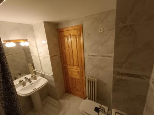 a bathroom with a sink and a toilet and a wooden door at InmoCyma Pico Posets Benasque in Benasque