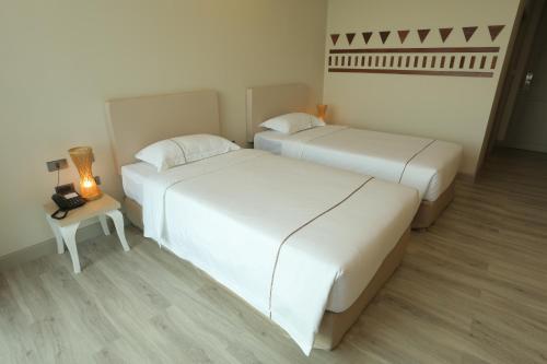 two beds in a room with a lamp and a table at Navela Hotel & Convention in Ratchaburi