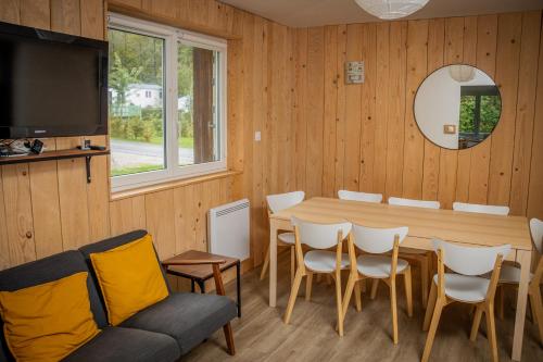 une pièce avec une table, des chaises et une télévision dans l'établissement Maison familiale 3 chambres au calme dans la nature, à Gérardmer
