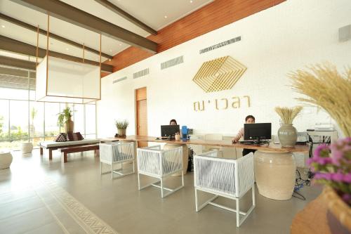 two people sitting at a table with laptops in a room at Navela Hotel & Convention in Ratchaburi