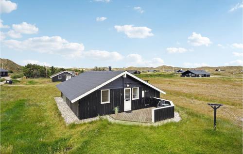 a small black house in a field with grass at Amazing Home In Ringkøbing With Sauna in Ringkøbing