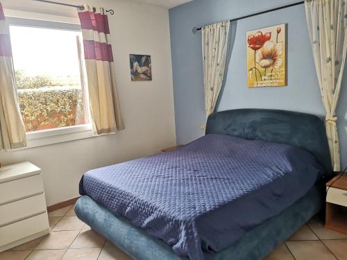 a bedroom with a blue bed and a window at Alloggio Residence Sa Tanca in Valledoria