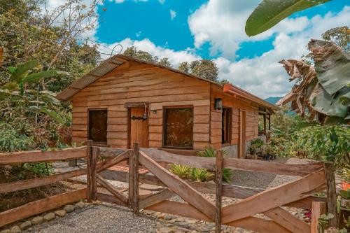a cabin in the woods with a wooden fence at La Tigra Rainforest Lodge in Fortuna