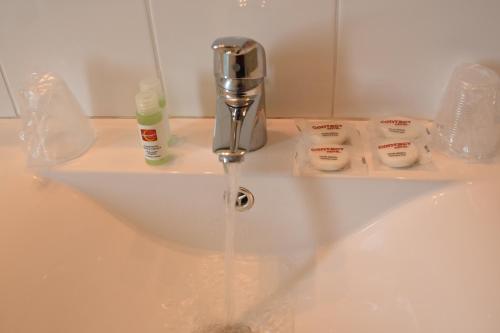 a bathroom sink with water running from a faucet at Hôtel Continental in Vierzon