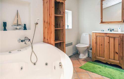 a bathroom with a tub and a sink and a toilet at Holiday Home Sletten Hadsund I in Helberskov