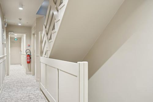 a hallway with white walls and a fire extinguisher at Hôtel Clémence in Paris