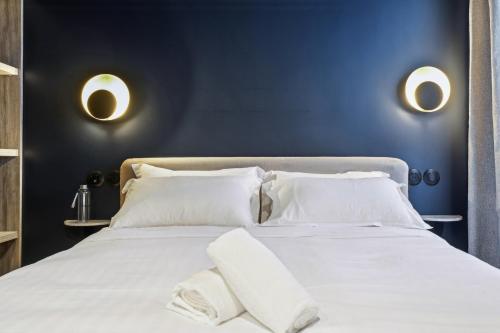 a blue bedroom with a white bed with white pillows at Hôtel Clémence in Paris